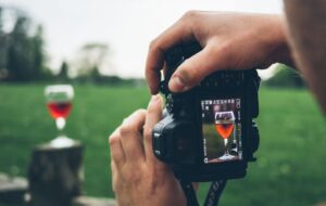 ragazzo con macchina fotografica che fotografa un bicchiere di vino