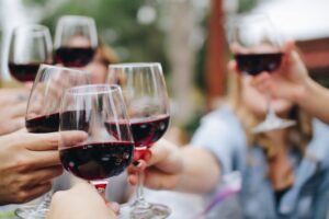 Persone che brindano con bicchieri di vino rosso